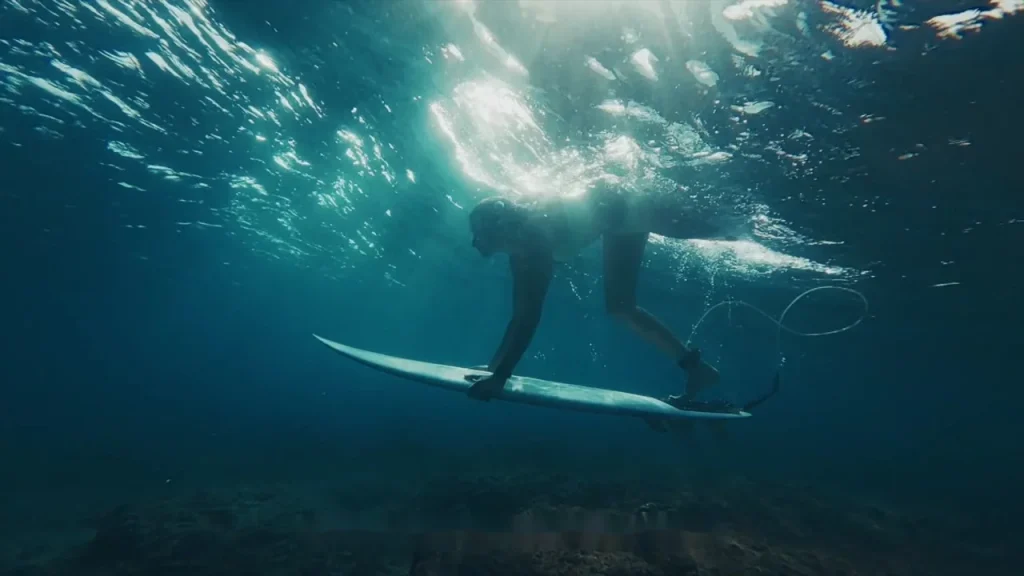 Surfeur sous la surface de l’océan tenant sa planche de surf